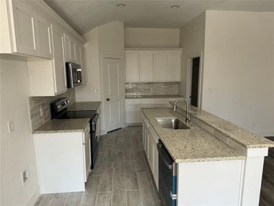 Kitchen with sink, appliances with stainless steel finishes, white cabinets, and backsplash