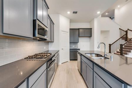 Kitchen featuring sink, gray cabinetry, stainless steel appliances, light hardwood / wood-style floors, and decorative backsplash