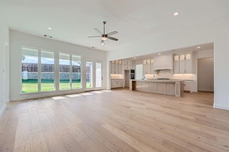 Unfurnished living room with ceiling fan, sink, and light wood-type flooring