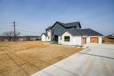 Modern farmhouse style home with an attached garage, brick siding, concrete driveway, roof with shingles, and a front lawn