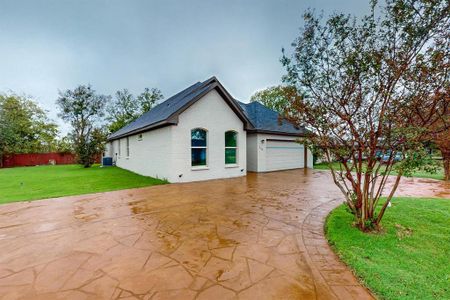 View of front of home featuring a garage, a front yard, and central AC