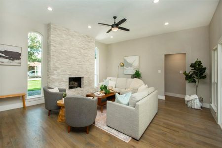 Living room with ceiling fan, a wealth of natural light, dark hardwood / wood-style floors, and a stone fireplace