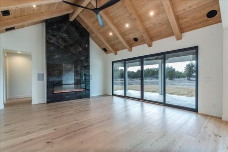 The stunning family room features 17' ceilings accentuated by exquisite Alder wood beams, custom-crafted in Oregon, along with a tongue-and-groove ceiling that adds to the room's inviting warmth.