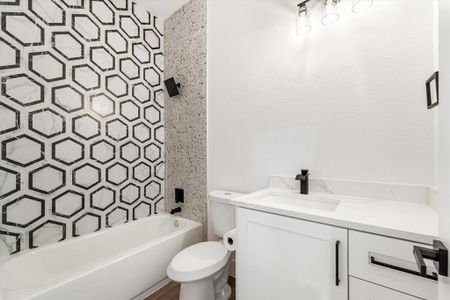 A complete bathroom equipped with a shower and tub combination, along with a charming vanity featuring quartz countertops.