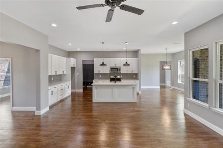 Kitchen featuring backsplash, white cabinets, a center island with sink, and stainless steel appliances