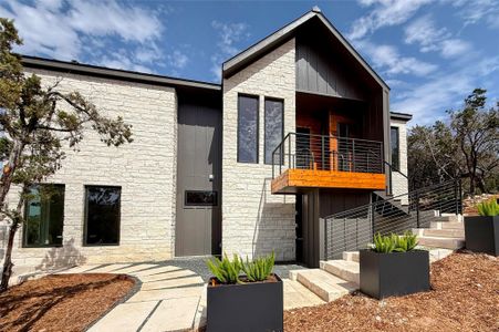 Modern home featuring stone siding, a balcony, board and batten siding, and stairs