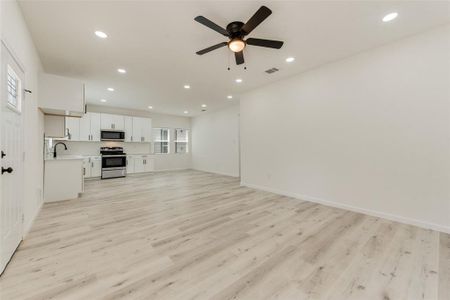 Unfurnished living room featuring light wood-type flooring, ceiling fan, plenty of natural light, and sink