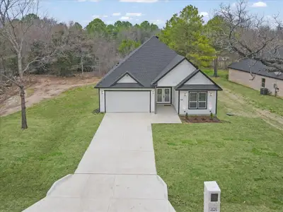 View of front of property with a shingled roof, a front yard, concrete driveway, and a garage