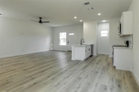 Kitchen with ceiling fan, white cabinets, light hardwood / wood-style flooring, and appliances with stainless steel finishes