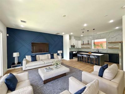 VIRTUALLY STAGING - This is a spacious, open-concept living area with a modern kitchen, featuring a bold blue accent wall, elegant lighting, and stylish finishes. The room is filled with natural light and designed for comfort and functionality.