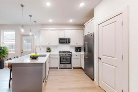 Kitchen with stainless steel appliances, hanging light fixtures, sink, a breakfast bar, and kitchen peninsula