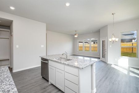 Kitchen with stainless steel dishwasher, sink, pendant lighting, hardwood / wood-style flooring, and white cabinets