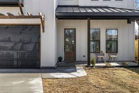 View of exterior entry featuring metal roof, a standing seam roof, concrete driveway, and board and batten siding