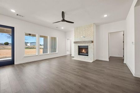 Unfurnished living room featuring ceiling fan, recessed lighting, a large fireplace, visible vents, and dark wood finished floors