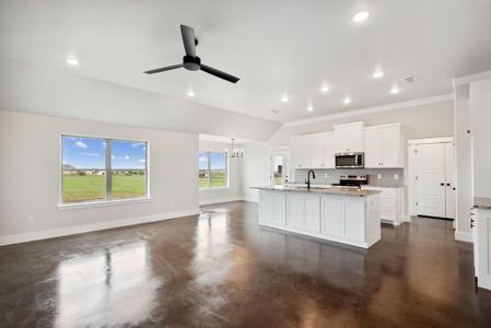 Kitchen with white cabinetry, tasteful backsplash, light stone counters, a kitchen island with sink, and stainless steel appliances