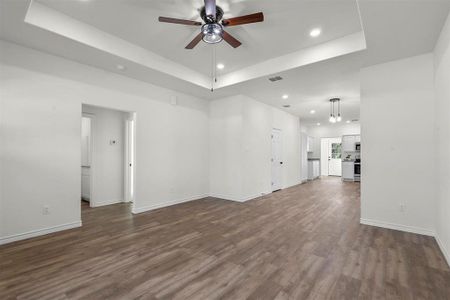 Unfurnished room featuring ceiling fan, a raised ceiling, and dark hardwood / wood-style floors