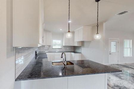 Kitchen with sink, dark stone counters, decorative light fixtures, decorative backsplash, and white cabinets