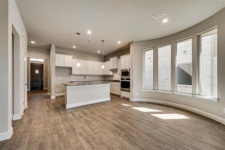 Kitchen featuring stainless steel appliances, white cabinets, and a center island with sink