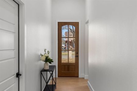 Doorway with light wood finished floors and baseboards