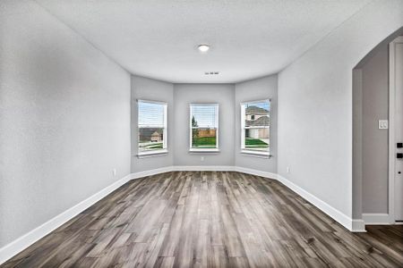 Unfurnished room featuring arched walkways, visible vents, dark wood-type flooring, a textured ceiling, and baseboards