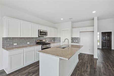 Kitchen with dark hardwood / wood-style flooring, an island with sink, white cabinets, appliances with stainless steel finishes, and sink