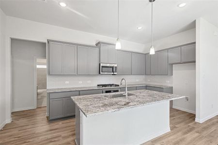 Kitchen featuring a kitchen island with sink, sink, light hardwood / wood-style floors, and appliances with stainless steel finishes