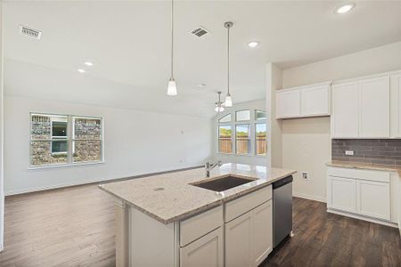 Kitchen with white cabinets, an island with sink, stainless steel dishwasher, dark wood-type flooring, and sink