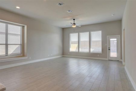 Empty room featuring ceiling fan, light hardwood / wood-style floors, and a wealth of natural light