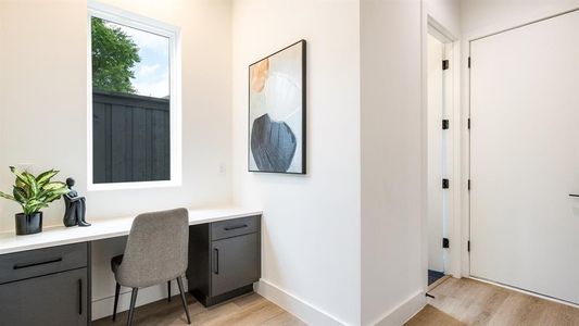 Office area with built in desk and light wood-type flooring