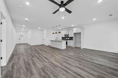 Unfurnished living room with wood-type flooring, sink, and ceiling fan