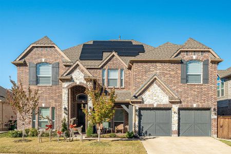 View of front of property featuring a front lawn, a garage, and solar panels