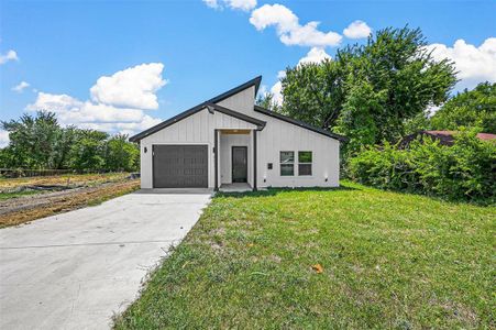 Modern farmhouse featuring a garage and a front lawn