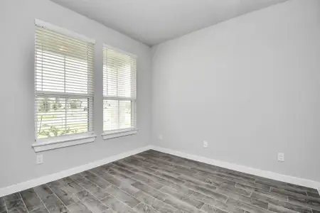 Experience the perfect blend of sophistication and warmth in this home office, boasting elegant wood-look tile flooring and flooded with natural light from expansive windows and French doors. Sample photo of completed home with similar floor plan. Actual colors and selections may vary.