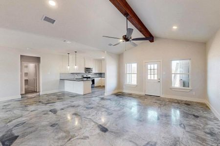 Unfurnished living room featuring visible vents, lofted ceiling with beams, a sink, ceiling fan, and baseboards