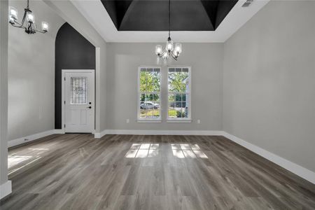 Unfurnished dining area featuring hardwood / wood-style flooring, a notable chandelier, and a raised ceiling