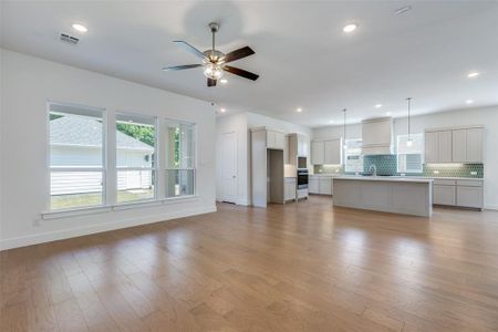 Unfurnished living room featuring ceiling fan, sink, and light hardwood / wood-style flooring