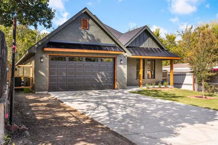 View of front of home with central AC unit and a garage