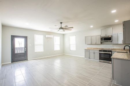 Kitchen featuring gray cabinetry, backsplash, appliances with stainless steel finishes, baseboards, and ceiling fan