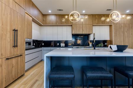 Kitchen with light hardwood / wood-style flooring, a kitchen breakfast bar, hanging light fixtures, and a large island