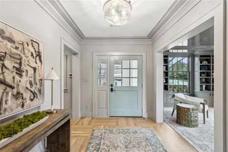 Doorway with a notable chandelier, baseboards, visible vents, and crown molding