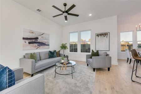 Living room featuring ceiling fan with notable chandelier and light wood-type flooring