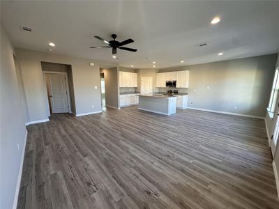 Kitchen featuring ceiling fan, a kitchen island, wood-type flooring, and white cabinetry