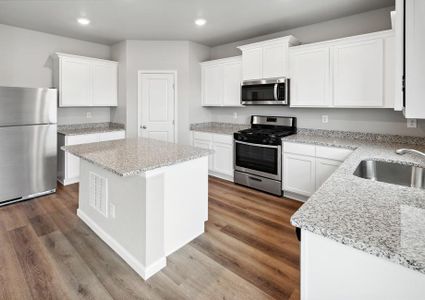 Designer kitchen with a large islands, sparkling countertops, and white cabinetry.