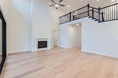 Unfurnished living room featuring ceiling fan, light wood-type flooring, and a high ceiling