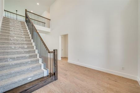 Staircase with wood-type flooring and a towering ceiling