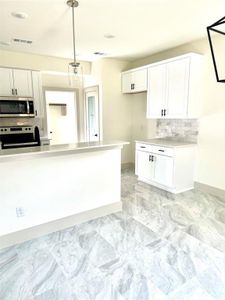 Kitchen with white cabinetry, electric range oven, decorative backsplash, and decorative light fixtures