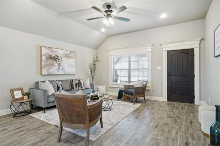 Living room with ceiling fan, vaulted ceiling, and hardwood / wood-style floors