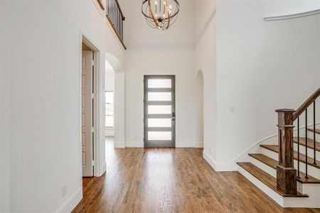 Foyer featuring a towering ceiling, an inviting chandelier, and hardwood / wood-style flooring