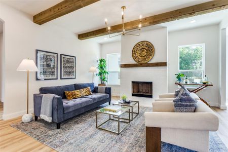 Living room featuring wood-type flooring, a fireplace, and beam ceiling