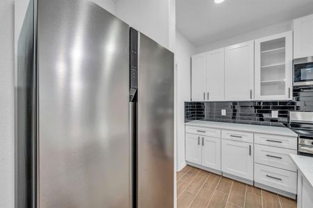 Kitchen with stainless steel appliances, white cabinetry, and tasteful backsplash